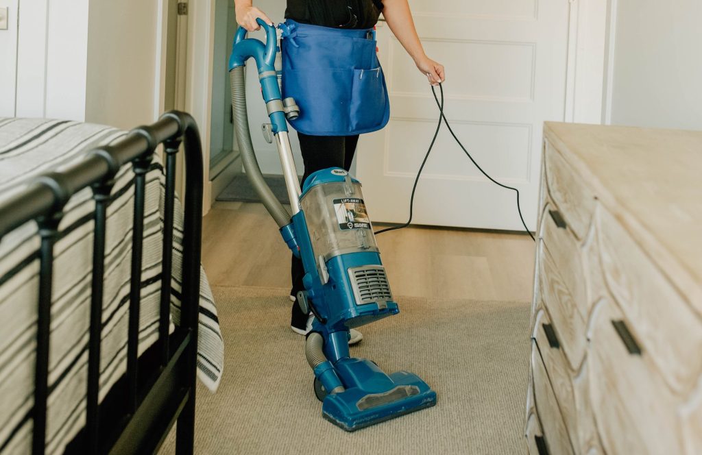 Professional cleaner using a HEPA vacuum in a St. George home.